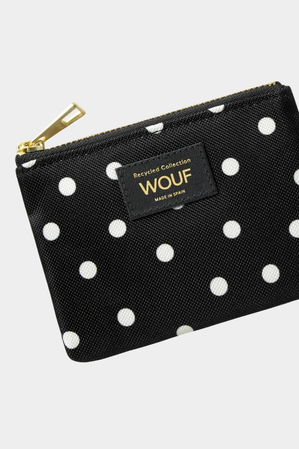 Detalle del monedero Wouf Grace con estampado de lunares blancos sobre negro, tirador dorado y etiqueta frontal
