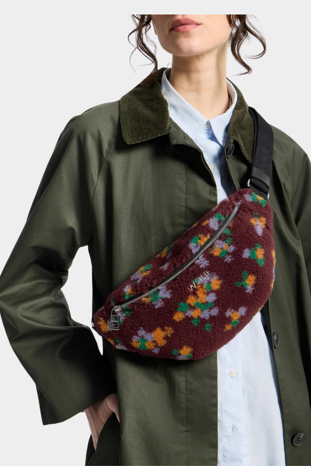 Riñonera Ella de Wouf llevada cruzada al pecho con textura teddy burdeos y pequeñas flores multicolor