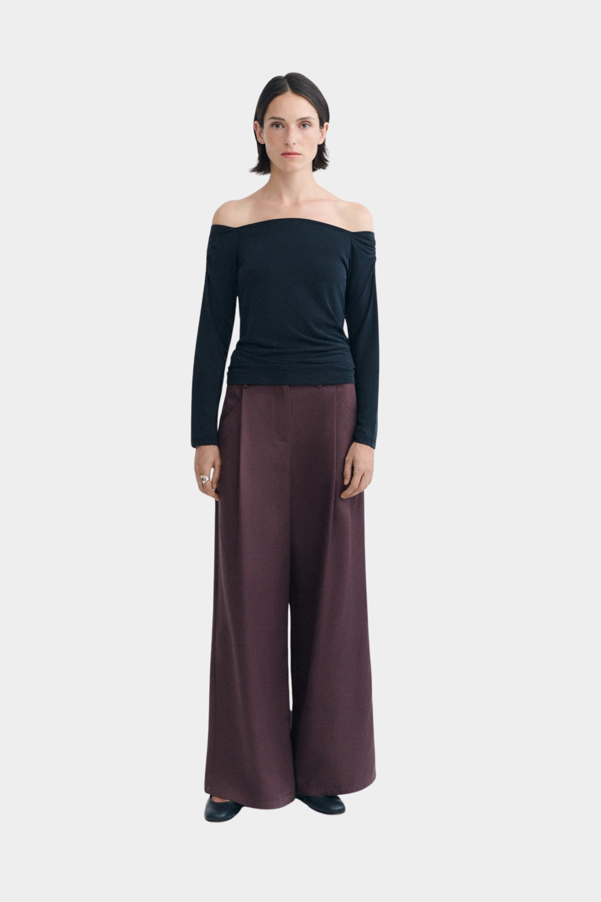 Top negro Berta de Thinking Mu puesto, con escote abierto de hombros y silueta slim de manga larga