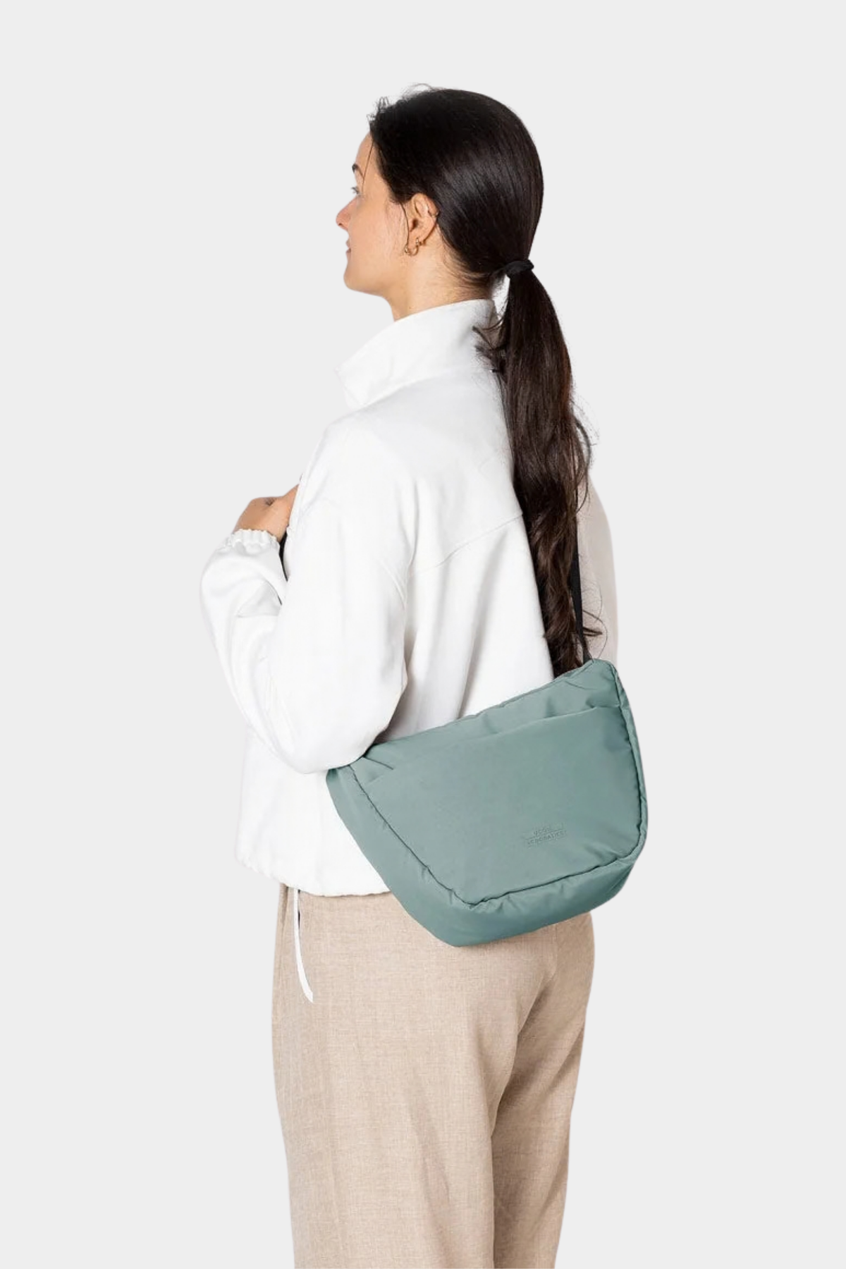 Bolso Ucon Acrobatics Adam Half-Moon Mini Pine Green llevado al hombro, con silueta de media luna y correa regulable