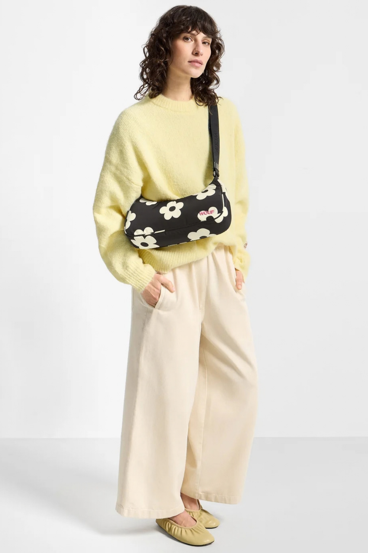 Bolso Wouf Night Daisy llevado cruzado, con estampado floral blanco sobre negro y correa ajustable