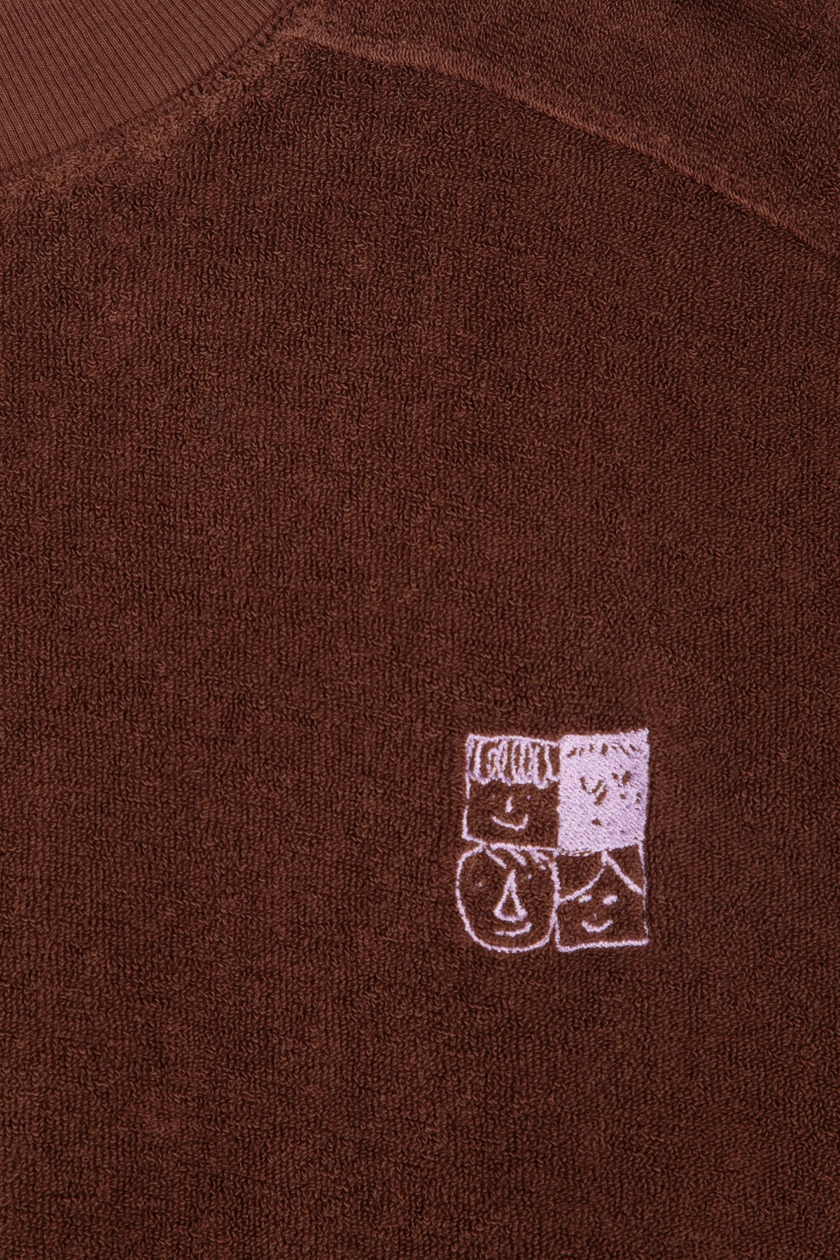 Detalle del pequeño gráfico frontal de la sudadera Mystery BC de Bobo Choses en algodón orgánico marrón oscuro
