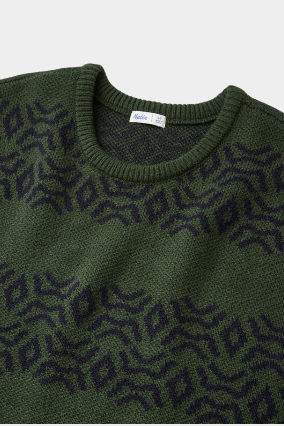 Detalle del jersey Villager de Katin USA en verde Pine con dibujo geométrico inspirado en tejido Kapa hawaiano
