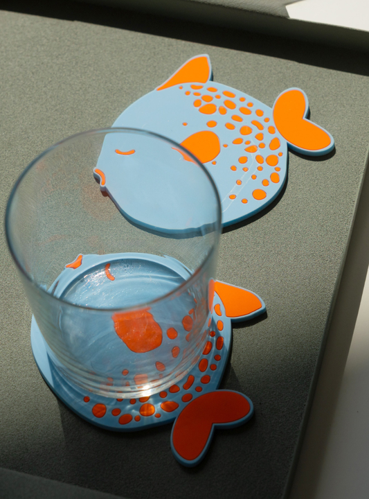 Pack de 4 posavasos Helio Ferretti Pez Globo en silicona flexible con diseño azul y naranja.