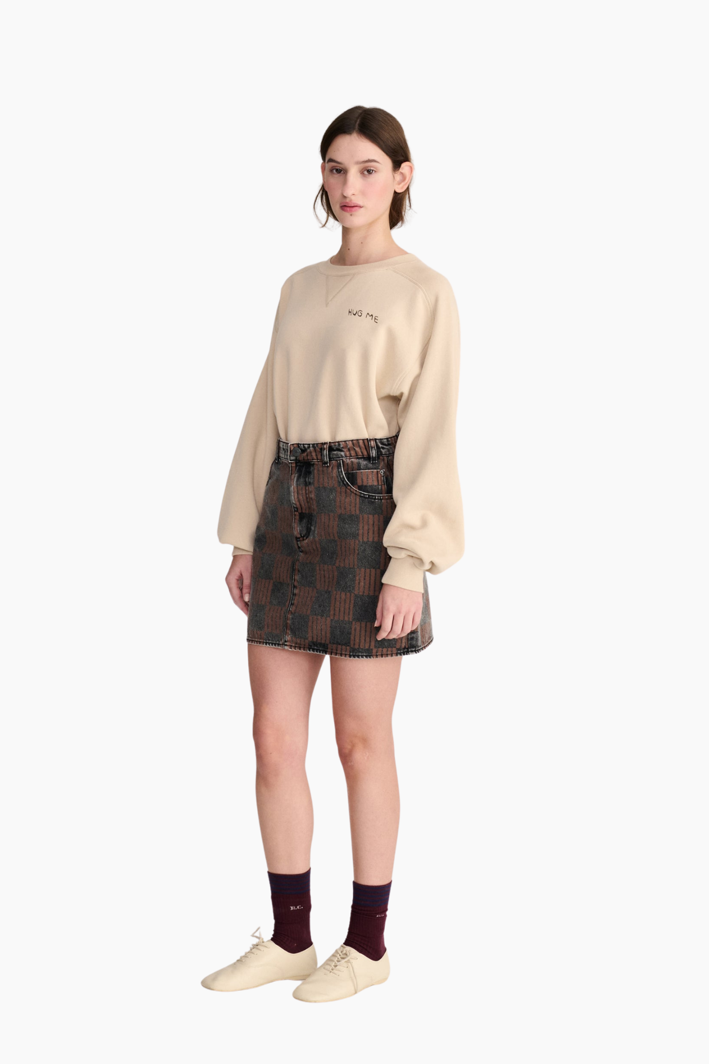 Look de mujer con sudadera beige Hug Me de Bobo Choses de corte holgado combinada con minifalda estampada