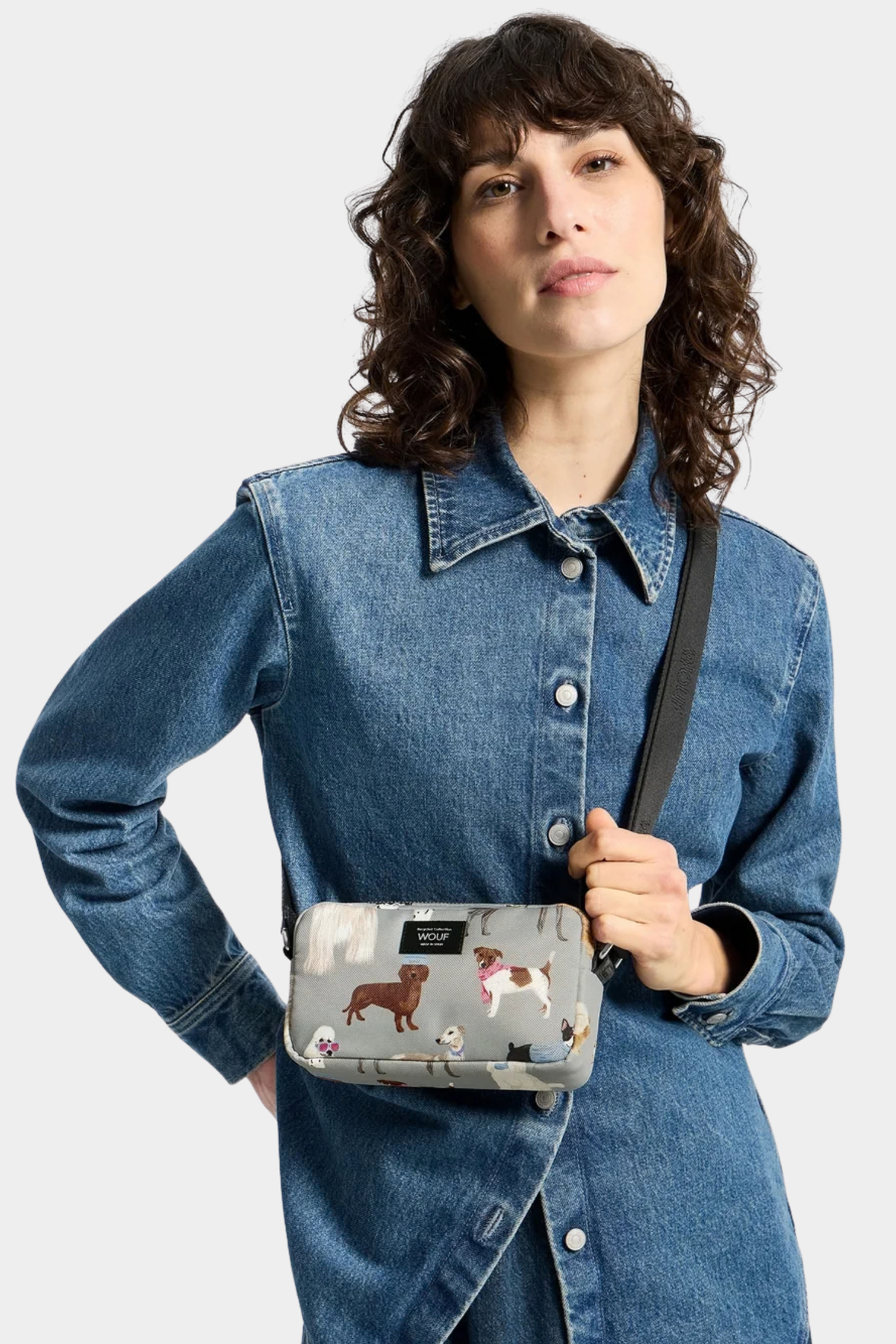 Mini bolso Wouf Puppy llevado como bandolera, con estampado de perros multicolor sobre fondo gris