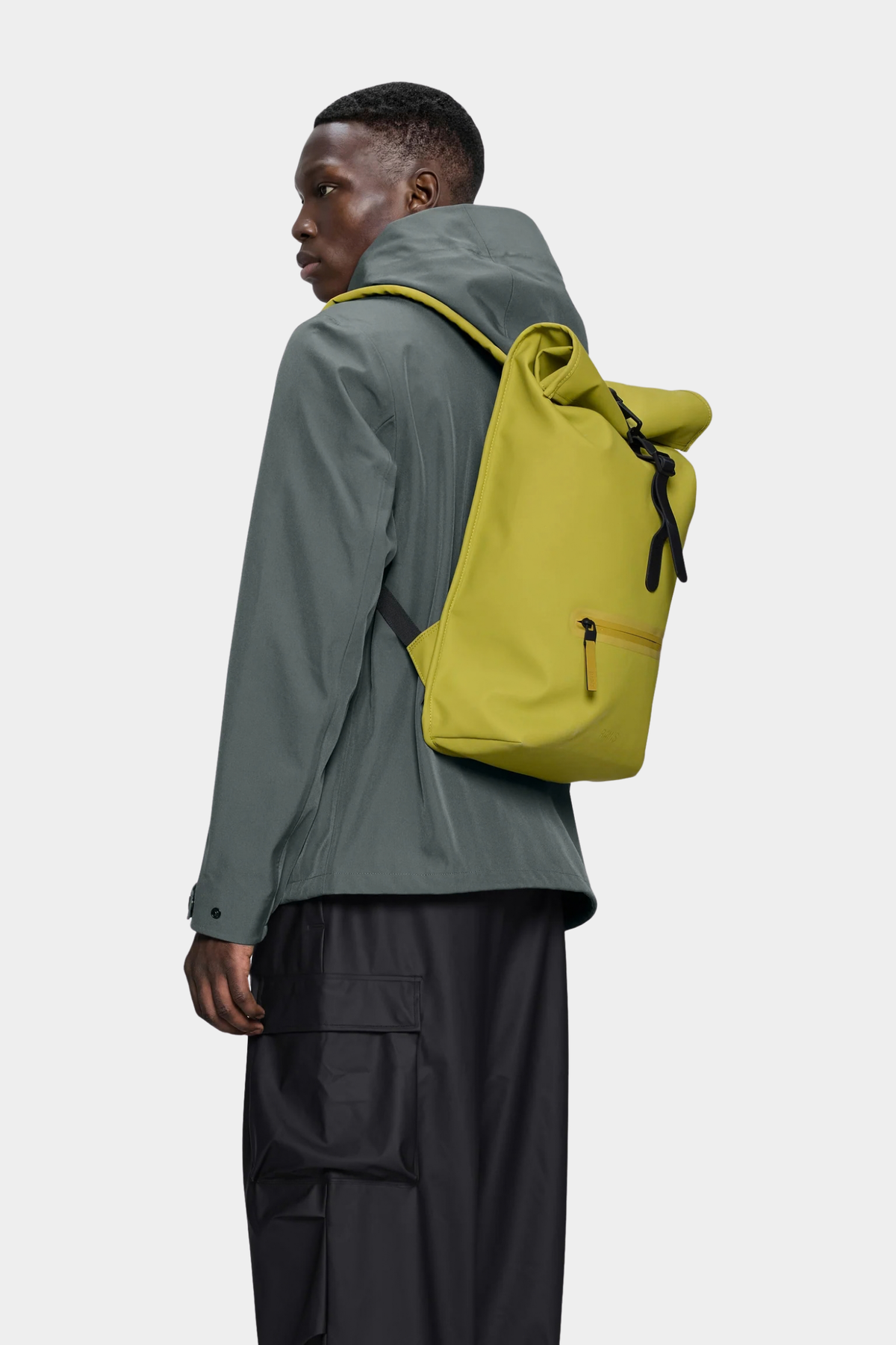 Mochila Rains Rolltop Rucksack Glow puesta, con correas acolchadas y diseño urbano para bici y ciudad